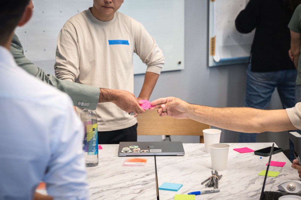 Workshop participants exchanging a pink sticky note